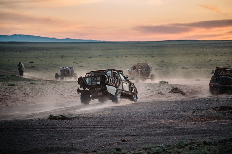 Convoy of Mad Max-style cars and motorbikes riding through Mongolian nature during the MadWay Rally.