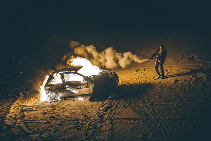 Man using a fire extinguisher to battle with a burning car during the MadWay Rally in Mongolia.
