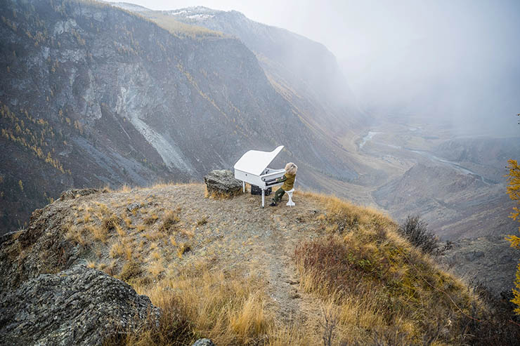 A child playing a white piano in the foggy mountainous landscape, during the MadWay Rally event. 