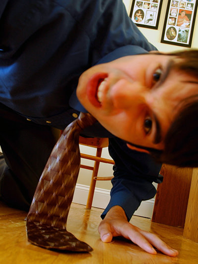 Man crouching on the floor and looking into a hidden camera; photo by Nick See.