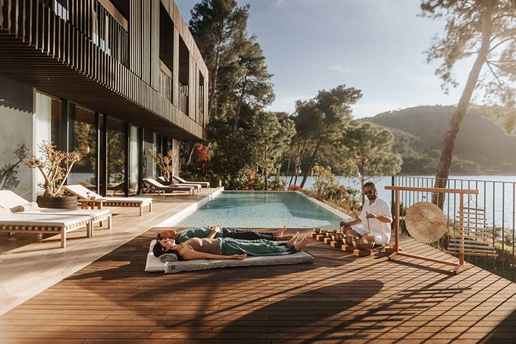 A couple enjoying a sound healing therapy by the outdoor pool and at the seaside Villa Uvala of Maslina Resort on Hvar Island, one of the best honeymoon resorts in Croatia; photo by Maslina Resort.