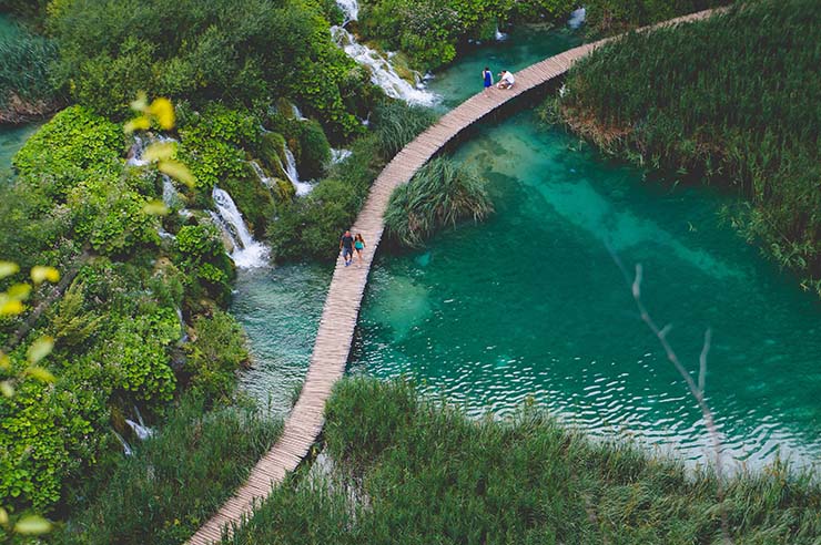 Aerial view of the wooden boardwalk passing over emerald green Plitvice Lakes and waterfalls, a popular honeymoon spot in Croatia; photo by Dominik Lange, Unsplash.