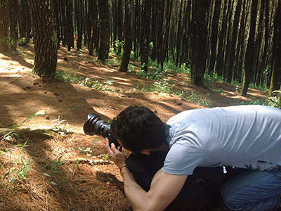 Travel blogger Ivan Kralj kneeling on the forest floor in Bukit Moko, Indonesia, while trying to photograph a fern dancing in the wind; photo by Fathin Naufal.