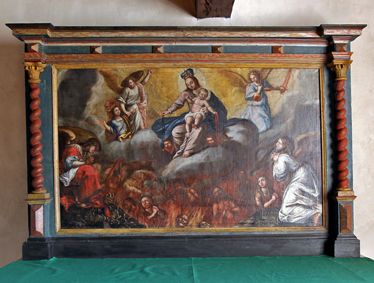 Poor Souls Altar in Beinhaus Leuk, Swiss ossuary in Wallis, showing the Mother of God sitting with baby Jesus and angels in the clouds, while the unfortunate ones are burning below them in the fires of hell; photo by Ivan Kralj.