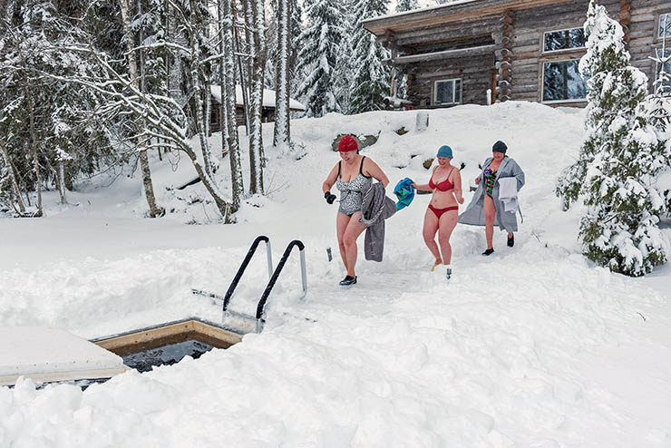Women walking on snow from Finnish sauna to an ice hole; photo by valokuvaaja Sonja Lahtinen.