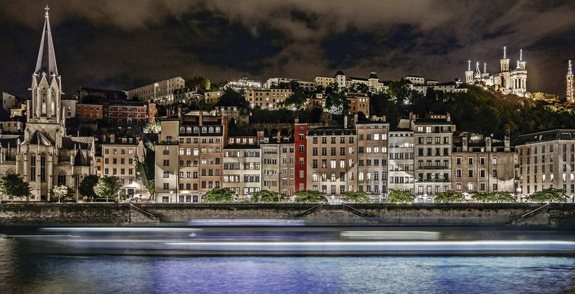Night panorama of Lyon's Saint-Georges neighborhood, with a touristic boat passing by; photo by Free Nomad, Unsplash.