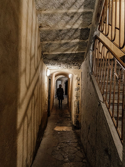 Woman walking through traboule, a narrow hidden passage through a building in Lyon, France, architecture from Renaissance period; photo by Nerissa J, Unsplash.