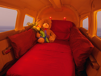 Teddy bear with flowers and candles on a red bed inside the Mile High Club plane in Traverse City.