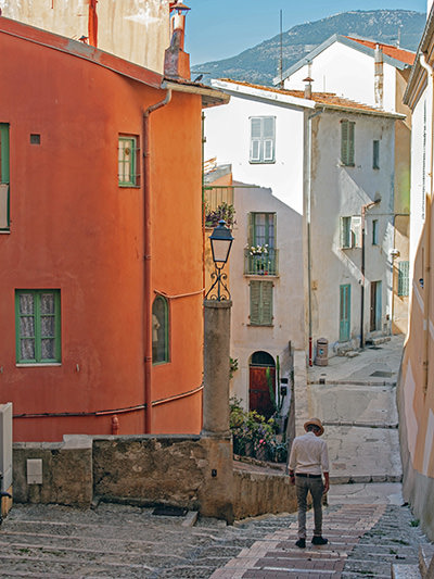 Man walking through a deserted town of Menton in Mediterranean France, during siesta; photo by Kamilla Isalieva, Unsplash.