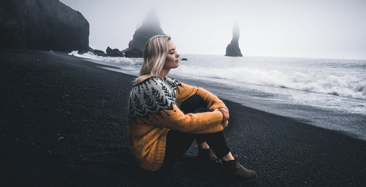 Woman taking a break on a black sand beach in Iceland; photo by Eriks Cistovs, Pexels.