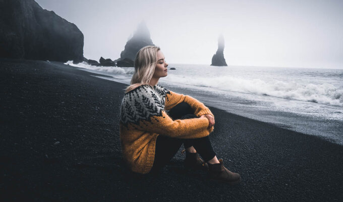 Woman taking a break on a black sand beach in Iceland; photo by Eriks Cistovs, Pexels.