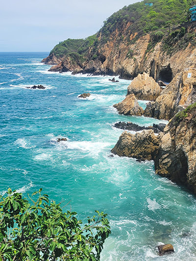 Waves around a promontory in Acapulco, Mexico, one of the best places to travel in 2024; photo by Daniel Apodaca, Unsplash.