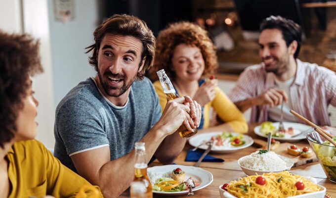 A group of happy people eating together, social dining; photo by Drazen Zigic, Freepik.