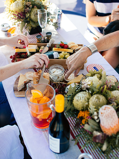 Food and drinks set on table with people around it, a concept of eaating with locals; photo by Rachel Claire, Pexels. 