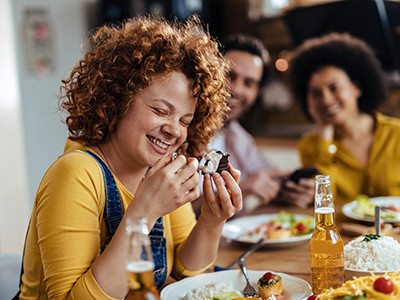 Woman having fun while eating with locals; photo by Drazen Zigic, Freepik.