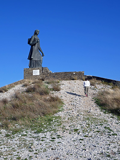 Woman of Zagori statue near Aspraggeli village in Greece, representing women of Pindus who carried supplies for Greek soldiers in the mountains during the 1940 Italian invasion; photo by Phil Venditti.