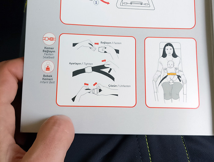 Airplane seat belt instructions in a safety card on Turkish Airlines flight.
