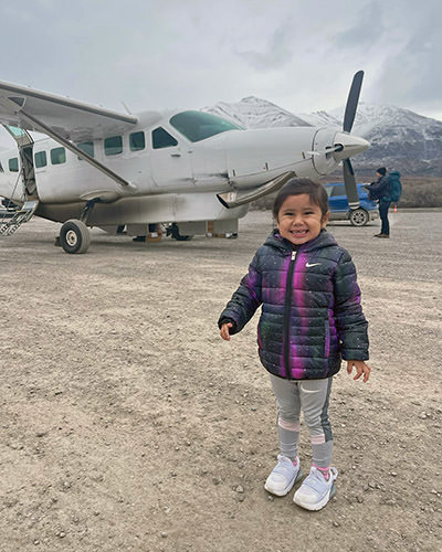 Journey Castillo, a three-year-old hiker on a mission to visit all U.S. national parks, standing in front of a single-engine plane bringing her to the Gates of Arctic National Park in Alaska.