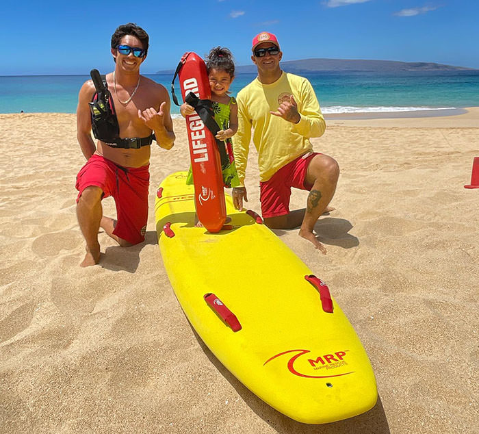 Three-year-old hiker and national parks regular Journey Castillo with lifeguards on Hawaii Beach.