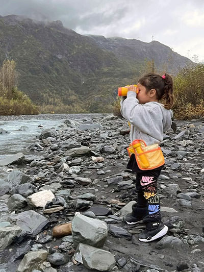 Journey Castillo looking through her Melissa-and-Doug binoculars while observing wildlife in one of many U.S. national parks.