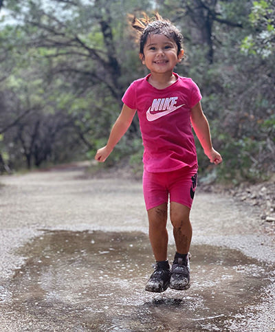 Three-year-old Journey Castillo, dressed in Nike wear, stepping into a mud.