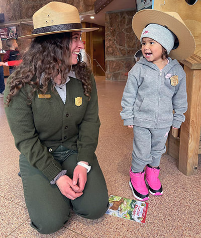 Journey Castillo as junior park ranger speaking to a real park ranger at Rocky Mountain National Park, one of 63 U.S. national parks she visited before turning 3.