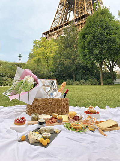 Decadent picnic on a lawn with Eiffel Tower in the background, by Patricia, Eatwith; one of Valentine food gift ideas.