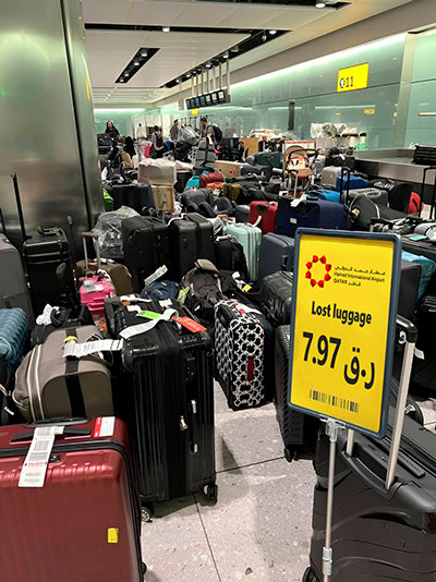 A mess of suitcases supposedly displayed at Hamad International Airport in Doha, with a sale sign offering lost luggage for 7.97 Qatari Rials per piece; one of many lost luggage scam making rounds on Facebook.