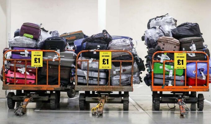 Piled-up suitcases with bright yellow sign advertising the lost luggage sale at London Gatwick Airport, claiming to offer a bag for 1 pound; one of many photoshopped images in global lost luggage scam.