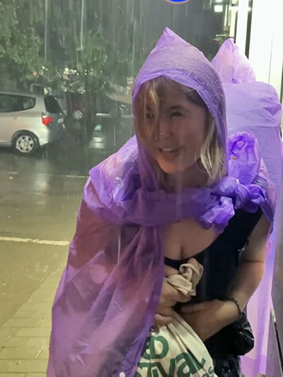 Rosa in a raincoat on a flooded street of Tbilisi, Georgia, during the slow travel adventure trip to Australia.