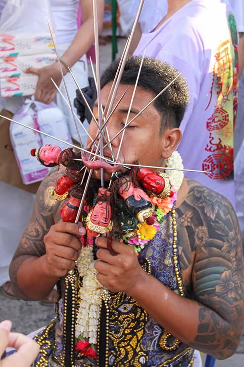 A man holding a dozen of spikes piercing his lower lip, at Jor Soo Goong Naka Shrine, during Jay or Phuket Vegetarian Festival, also known as Thailand's self-mutilation festival; photo by Ivan Kralj.
