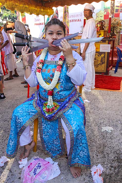 Sirinnicha Thampradit, a female ma song (spirit medium) holding three swords piercing through her right cheek at Jor Soo Goong Naka Shrine, during Jay or Phuket Vegetarian Festival, also known as Thailand's self-mutilation festival; photo by Ivan Kralj.