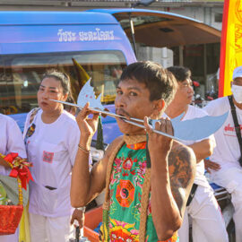 A man with two metal pieces of weapon passing through his pierced cheeks and mouth, at Jor Soo Goong Naka Shrine, during Jay or Phuket Vegetarian Festival, also known as Thailand's self-mutilation festival; photo by Ivan Kralj.