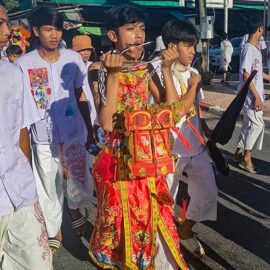 A young man with pierced cheeks walking in a street procession through Phuket during Jay Vegetarian Festival, also known as Thailand's self-mutilation festival; photo by Ivan Kralj.