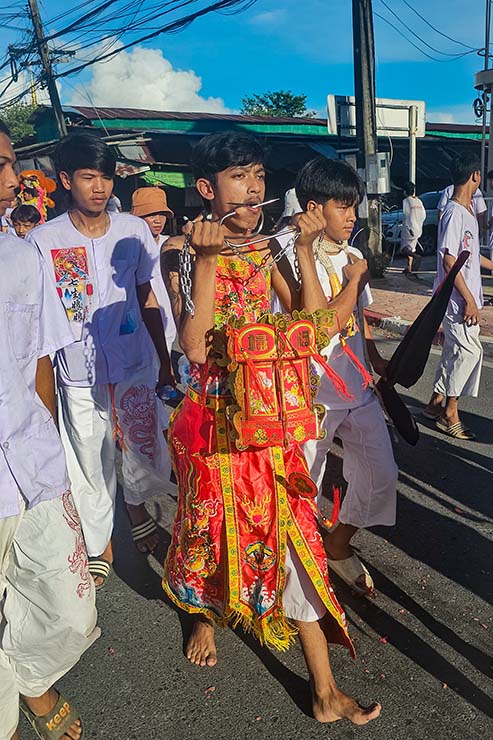 A young man with pierced cheeks walking in a street procession through Phuket during Jay Vegetarian Festival, also known as Thailand's self-mutilation festival; photo by Ivan Kralj.