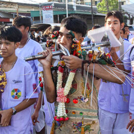 A young man with heavily pierced cheeks walking in a street procession through Phuket during Jay Vegetarian Festival, also known as Thailand's self-mutilation festival; photo by Ivan Kralj.