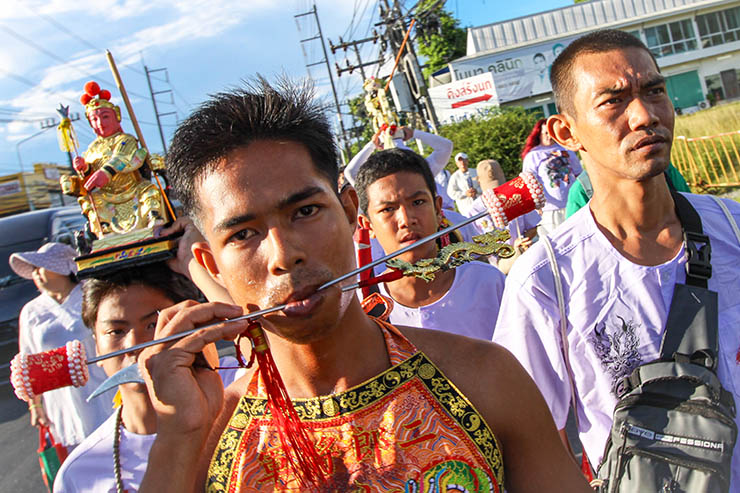 A close-up of a man with pierced cheeks, walking in a street procession through Phuket during Jay or Vegetarian Festival, also known as Thailand's self-mutilation festival; photo by Ivan Kralj.