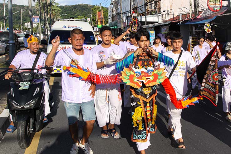 A young man with dragons hanging from his cheek-piercing hooks, walking in a street procession through Phuket during Jay or Vegetarian Festival, also known as Thailand's self-mutilation festival; photo by Ivan Kralj.