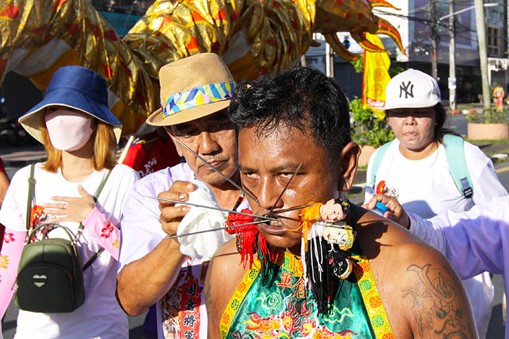 A man with several spikes piercing his cheeks, walking in a street procession through Phuket during Jay or Vegetarian Festival, also known as Thailand's self-mutilation festival; photo by Ivan Kralj.