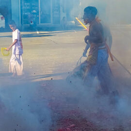 A ma song (spirit medium) with pierced cheeks, walking through the smoke created by exploding firecrackers in the streets of Phuket, during Jay or Phuket Vegetarian Festival; photo by Ivan Kralj.
