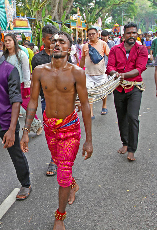 Hindu devotee with tongue and cheeks pierced with little spears (alavu kavadi) pulling vette mulle kavadi (hooks with attached ropes in the skin of his back) in honor of Lord Murugan, during Thaipusam Festival in Penang, Malaysia; photo by Ivan Kralj.