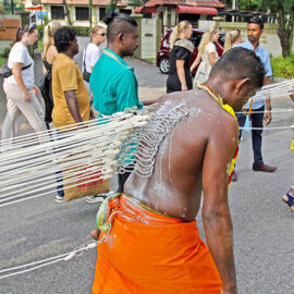 Two Hindu devotees pulling vette mulle kavadi (hooks with attached ropes in the skin of their back) in honor of Lord Murugan, during Thaipusam Festival in Penang, Malaysia; photo by Ivan Kralj.