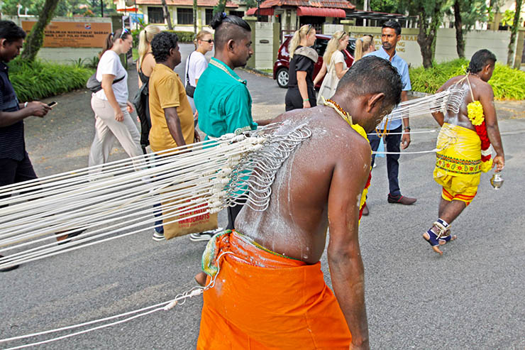 Two Hindu devotees pulling vette mulle kavadi (hooks with attached ropes in the skin of their back) in honor of Lord Murugan, during Thaipusam Festival in Penang, Malaysia; photo by Ivan Kralj.