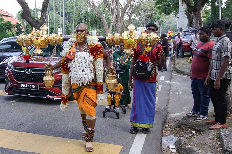 Hindu devotee carrying idumban kavadi (a pole) on his shoulders, and with pierced cheeks and tongue (alavu kavadi) in honor of Lord Murugan, during Thaipusam Festival in Penang, Malaysia; photo by Ivan Kralj.
