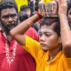 A female Hindu devotee carrying paal kudam (milk pot) on her forehead, in honor of Lord Murugan, during Thaipusam Festival in Penang, Malaysia.