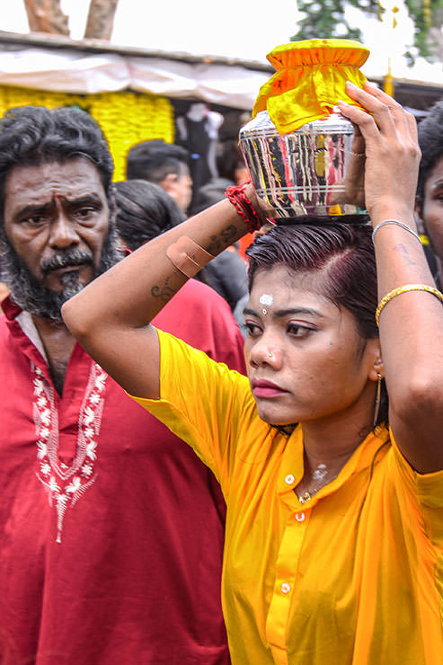 A female Hindu devotee carrying paal kudam (milk pot) on her forehead, in honor of Lord Murugan, during Thaipusam Festival in Penang, Malaysia.