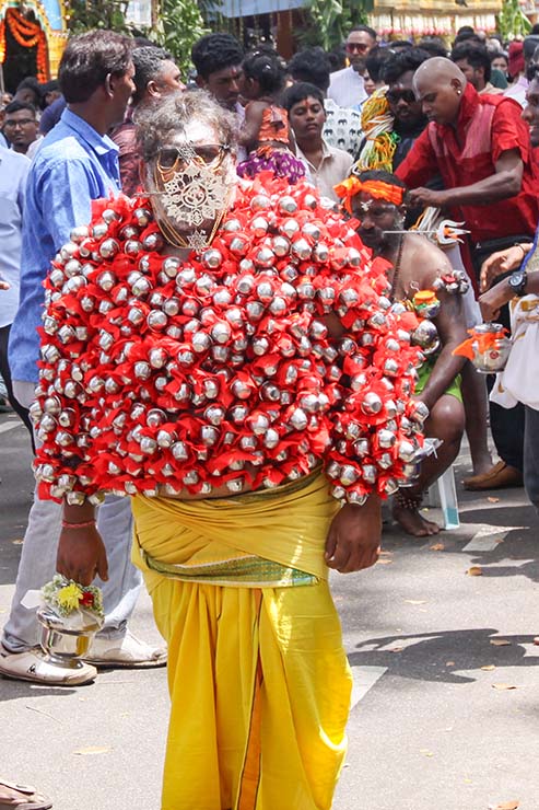 An older Hindu devotee carrying koodam mulle kavadi - milk pots pierced on his torso, and with cheeks and tongue pierced with little spears (alavu kavadi) in honor of Lord Murugan, during Thaipusam Festival in Penang, Malaysia; photo by Ivan Kralj.