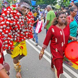 Hindu devotee with a painful facial expression, carrying koodam mulle kavadi - milk pots pierced on his torso, and with cheeks pierced with little spears (alavu kavadi) in honor of Lord Murugan, during Thaipusam Festival in Penang, Malaysia; photo by Ivan Kralj.