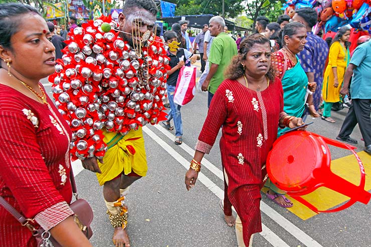 Hindu devotee with a painful facial expression, carrying koodam mulle kavadi - milk pots pierced on his torso, and with cheeks pierced with little spears (alavu kavadi) in honor of Lord Murugan, during Thaipusam Festival in Penang, Malaysia; photo by Ivan Kralj.