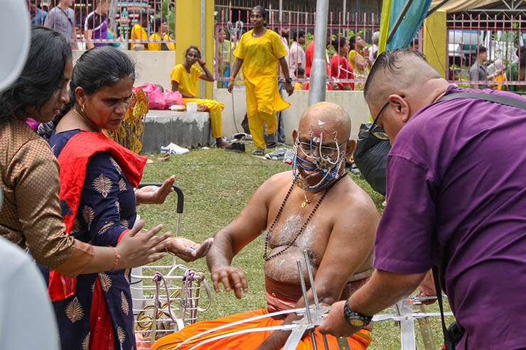 A man with pierced facial skin sitting near Waterfall Hilltop Temple during Thaipusam in Penang, Malaysia; photo by Ivan Kralj.